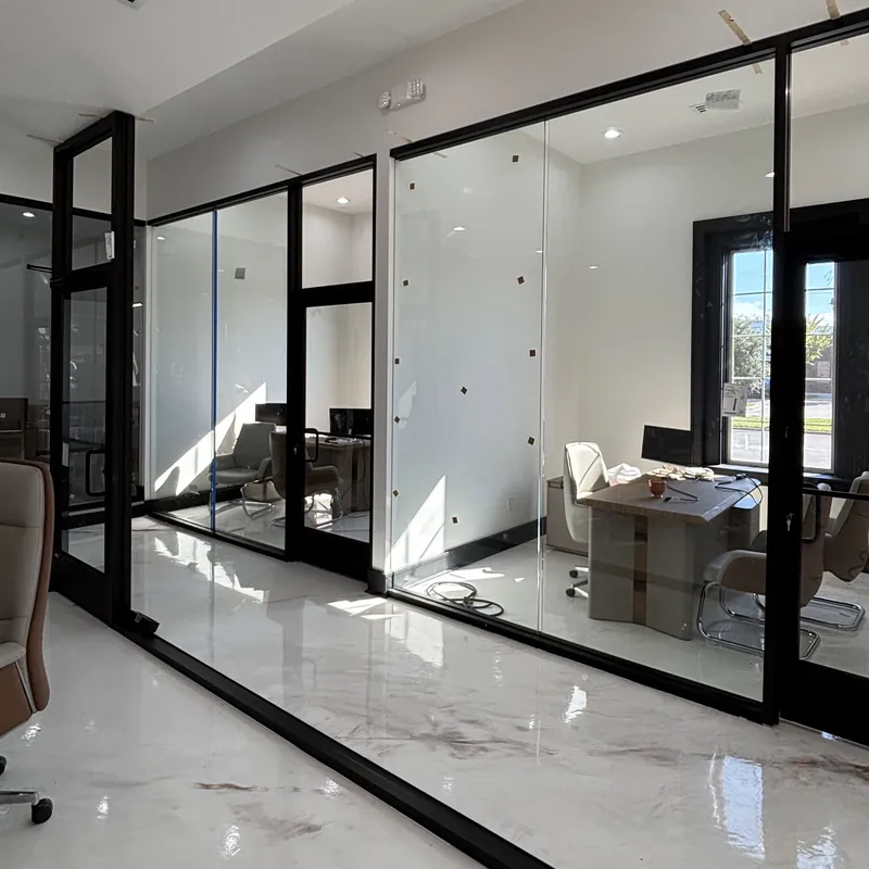 Black-framed glass office walls and doors along a bright corridor